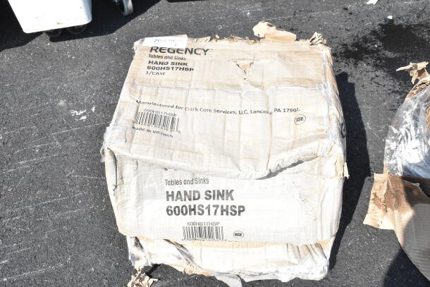 Box of Regency 600HS17HSP wall-mounted hand sink, new with scratches and dents. Contains size and branding labels.