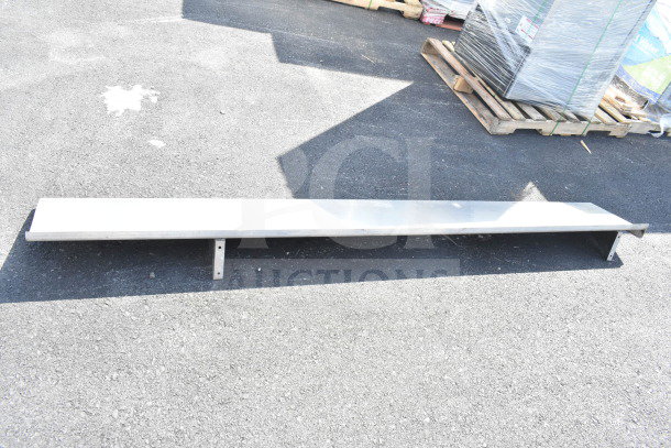 Metal shelf, long and narrow, with mounting brackets, in used condition, suitable for storage or display.