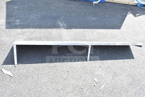 Metal shelf with mounting brackets on asphalt; lightly used, suitable for storage or display.