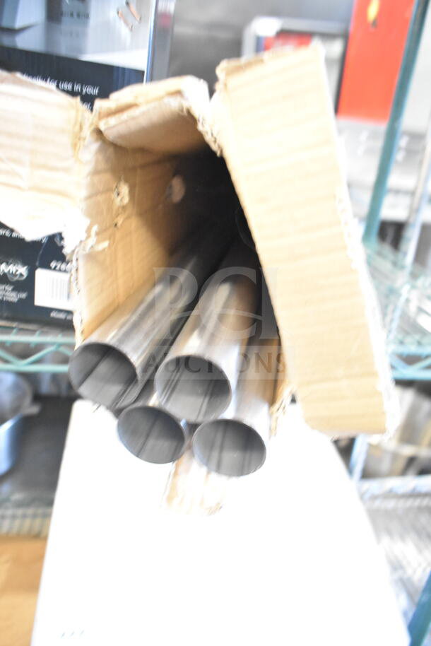 Box of four metal posts, brand new with visible scratches and dents, in partially opened cardboard packaging.