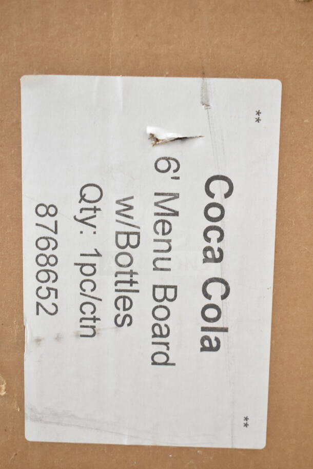 Cardboard packaging with a label for a 6' Coca Cola menu board with bottles. Scratch and dent noted. Item code 8768652.
