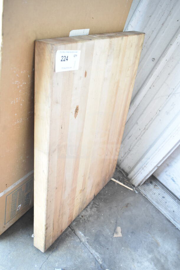 Butcher block wooden cutting board with visible wear, item label "224," rectangular shape, light wood tones.