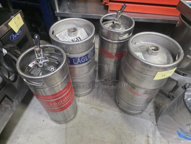 Lot of 4 metal kegs with tap fittings. Each keg features different brewery branding and appears in used condition.