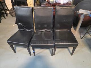 Lot of 6 black faux leather dining chairs, padded seats, slight wear on upholstery, modern design, wooden legs.