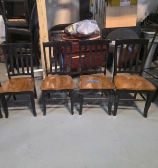 Lot of 4 dining chairs with wooden seats and black slatted backs. Used condition, ideal for dining room or kitchen.