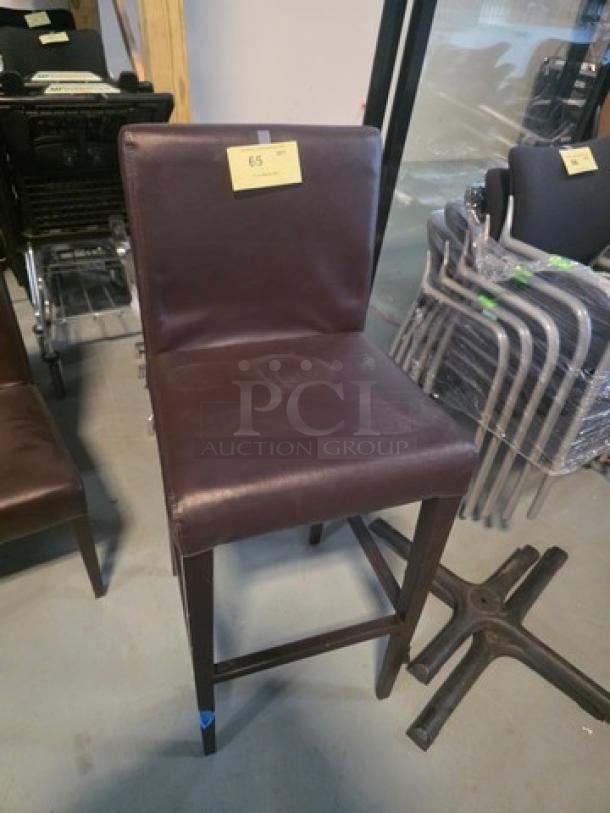 Brown leather bar stool with cushioned seat and back, wooden legs. In good condition with a label marked "65".