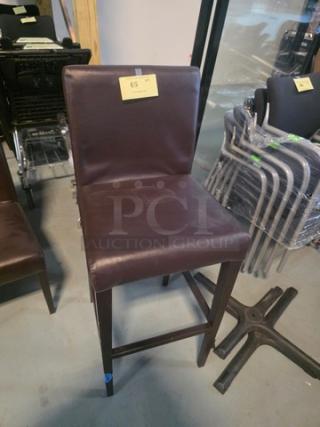 Brown leather bar stool with cushioned seat and back, wooden legs. In good condition with a label marked "65".