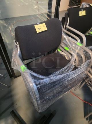 Lot of 5 stacking chairs with black fabric seating and gray powder-coated frames, wrapped for protection.