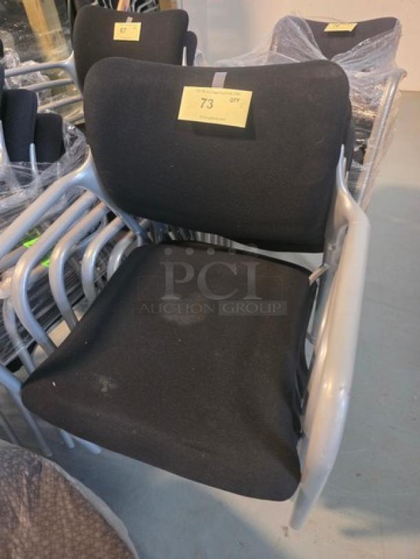 Lot of 5 stacking chairs with black fabric seats and gray powder-coated frames. Visible wear on seats. Quantity label marked "73".