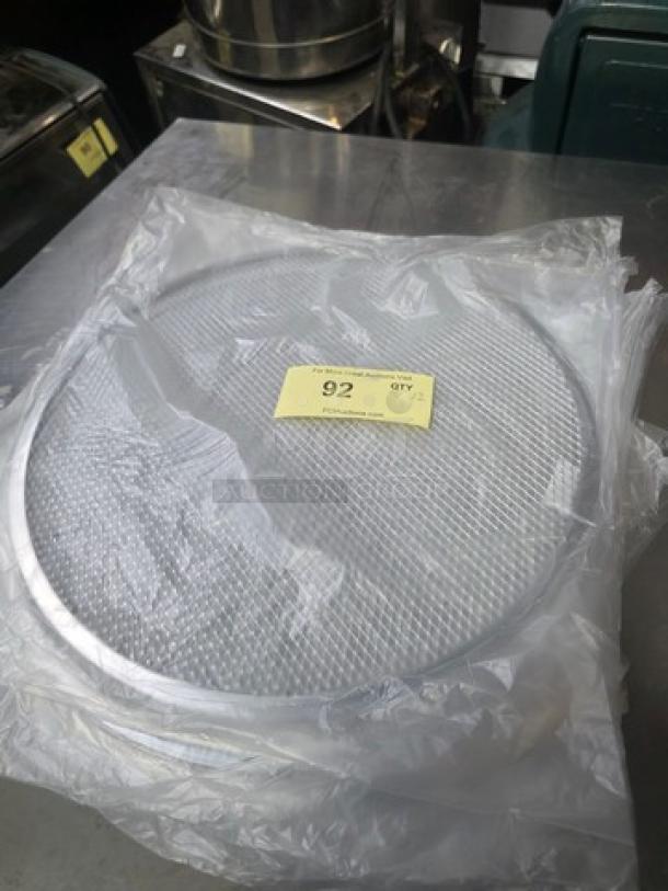 Lot of 12 aluminum pizza screens, 16 inches each. New condition, in plastic packaging with tag showing quantity and bid number.