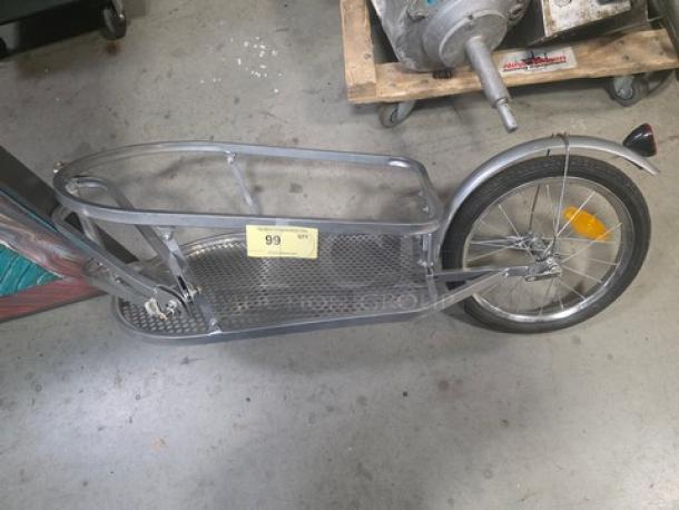 BOB Yak Single-Wheel Bicycle Cargo Trailer in silver, features metal frame, mesh cargo area, and reflectors. Auction tag marked "99".