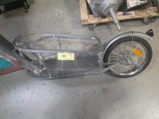 BOB Yak Single-Wheel Bicycle Cargo Trailer in silver, features metal frame, mesh cargo area, and reflectors. Auction tag marked "99".