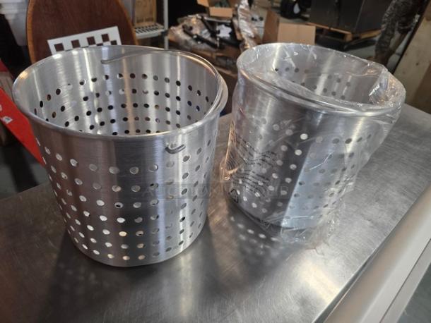 Lot of 2 Winco aluminum steamer baskets, one wrapped in plastic, featuring perforated sides, in excellent condition.