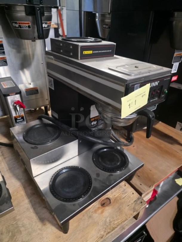 Bunn coffee maker with 4 warmers. Stainless steel, used condition. Model features include multiple heating plates and control panel.