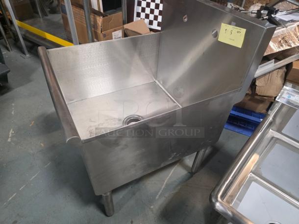 Commercial stainless steel utility sink, single compartment, freestanding, with backsplash. Visible wear, includes a drain.