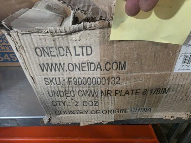 Damaged cardboard box labeled "Oneida Ltd" containing a lot of 23 8" round plates, SKU F9000000132, from China.