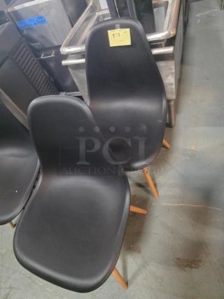 Lot of 2 armless dining chairs, black plastic seats, wooden legs, modern design. Excellent condition. Auction label visible.