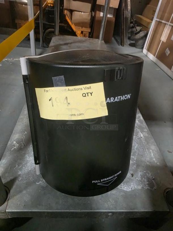 Black Marathon paper towel dispenser, cylindrical design, pull straight down mechanism, visible auction tag on front.