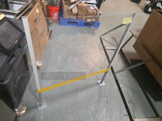 Freestanding sneeze guard with metal frame, clear acrylic panel, and yellow stripe. In good condition, ideal for counters.