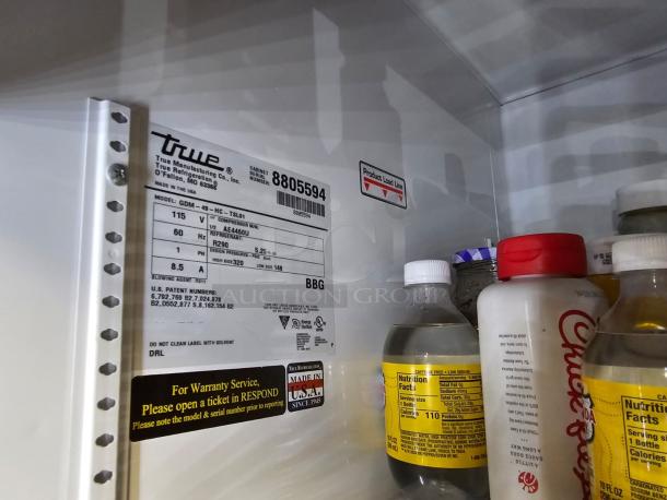 TRUE GDM-49 two-door refrigerator, tested and working. Interior label displays model and specs, bottles inside for size reference.