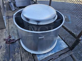 Industrial exhaust fan, metal casing, circular design, moderate wear, visible mounting components, sits on wooden surface.