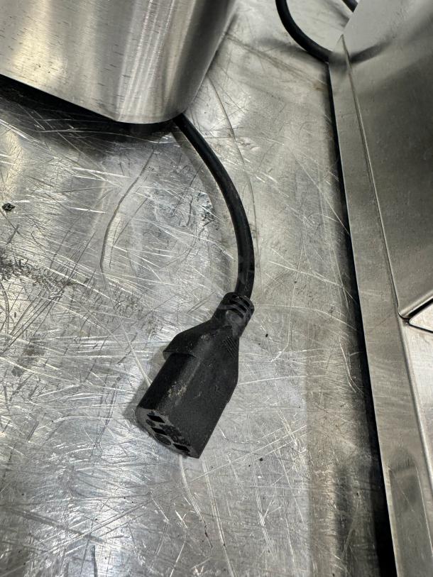 Farberware 4-liter deep fryer power cord on scratched metal surface. Cord intact, showing typical wear.