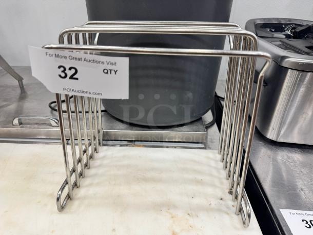 Stainless steel cutting board storage rack in good condition with seven slots, auction tag visible.