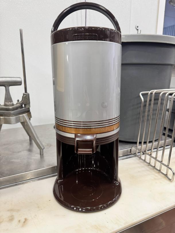 Brand new thermal beverage dispenser, brown and gray, with a spout and carrying handle.