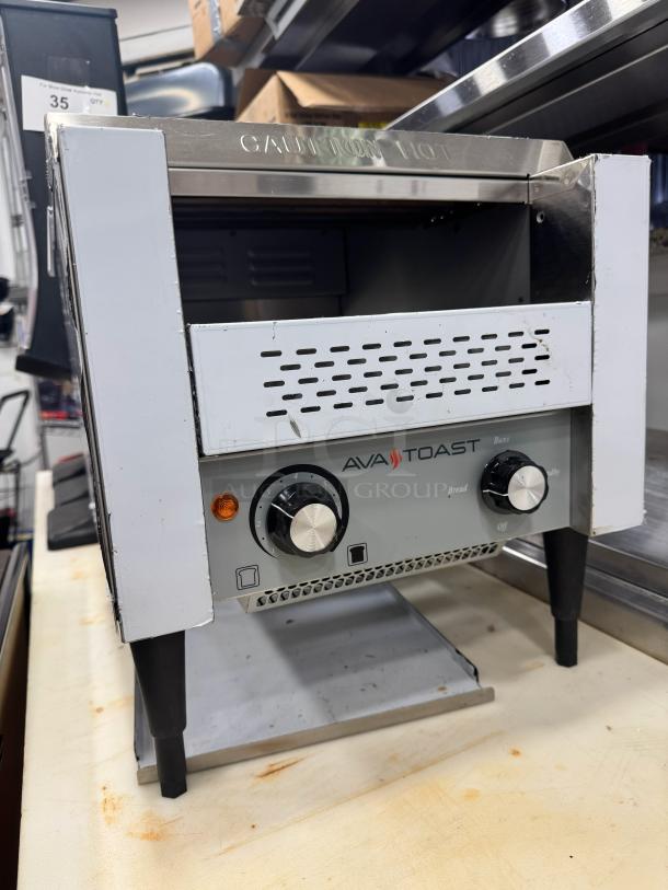 AvaToast CTA 7001 tabletop conveyor toaster, brand new. Features control knobs, warning label "CAUTION HOT."