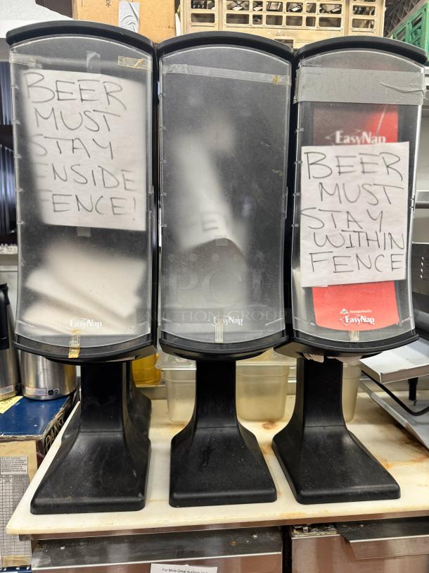Lot of 3 EasyNap napkin dispensers, black plastic, "Beer must stay inside fence" signs, used condition.