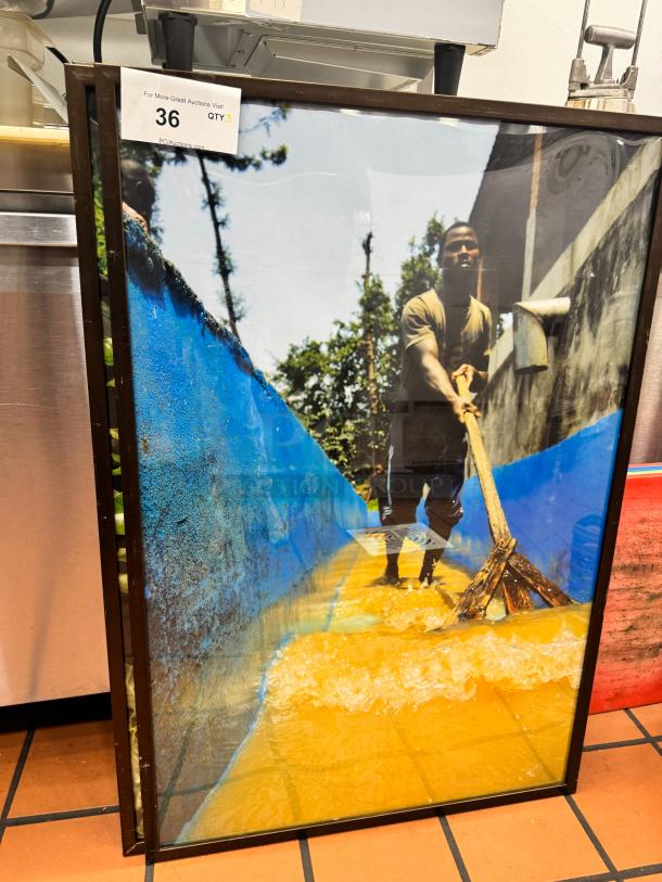 Framed art print titled "BIDX3" showing a person working with water, vibrant colors, black frame. Auction tag "36 QTY3" visible.