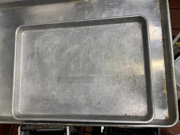 Lot of 7 metal baking pans, well-used with minor discoloration, stackable design, ideal for bulk baking.