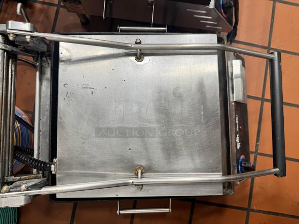 Star Pro-Max Panini Grill in used condition, stainless steel surface with wear marks, featuring sturdy handle and adjustable top plate.