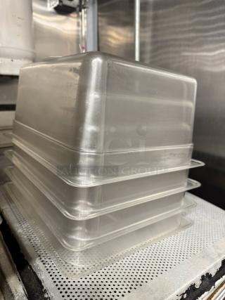 Stacked clear plastic food pans, model BIDX4, with visible markings for measurement, in good condition.