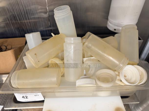 Lot of squeeze bottles in varying conditions. Includes caps and nozzles. Signs of use visible. Auction lot number 42.