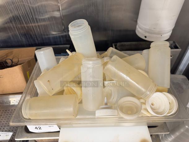 Lot of used squeeze bottles, varying conditions, in a plastic tray. Includes caps and lids. Sold as one lot.