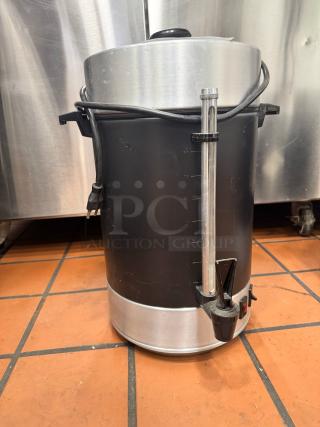 Stainless steel and black coffee urn with a level indicator and spout. Power cord wrapped around. Used condition.
