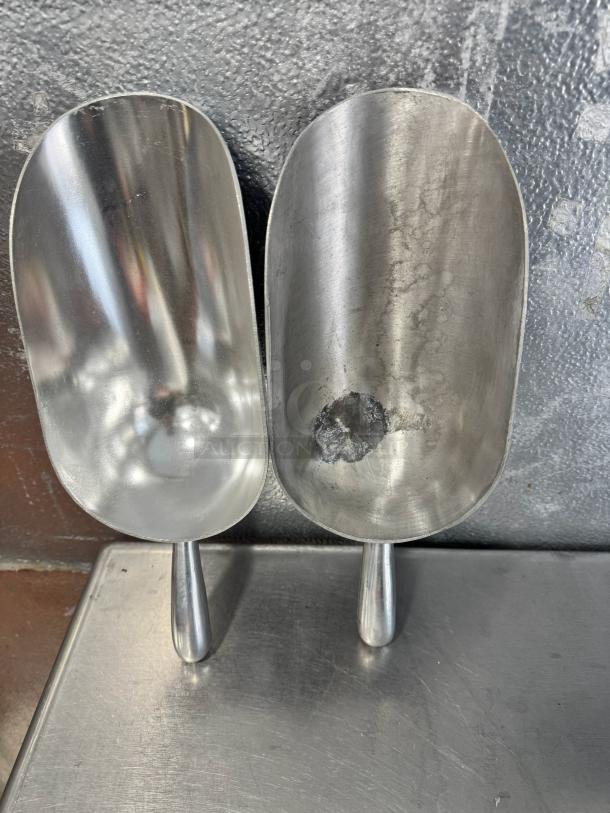 Lot of 2 aluminum scoops, 85oz each, showing slight wear; one with a visible dent. Collectively sold.