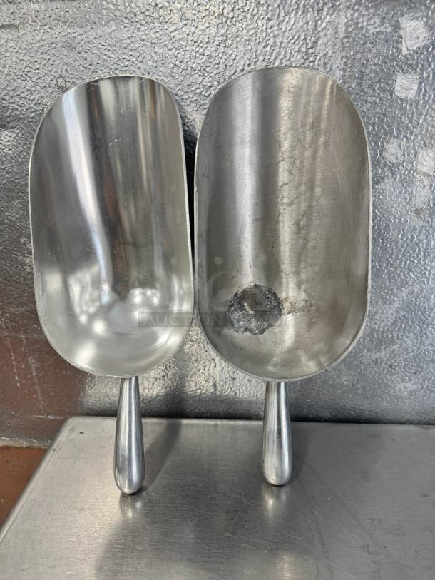 Lot of 2 aluminum scoops, 85oz each. One scoop in good condition, the other with visible wear and a large dent.