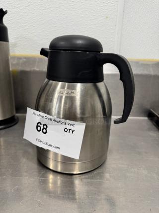 Stainless steel coffee carafe with black lid and handle, show signs of use. Auction label "68 QTY" visible, PCI Auctions.
