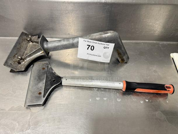 Lot of 2 griddle scrapers, one Chef Master brand with rubber grip, both with steel blades. Used condition, visible wear.