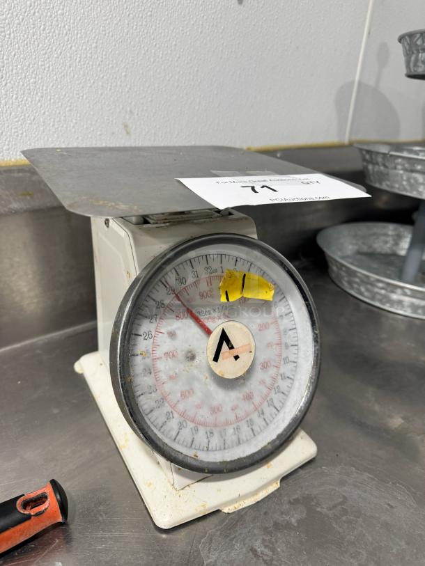 Vintage portion control scale with metal platform and dial face, marked with A logo. Shows signs of wear. Auction label: 71.