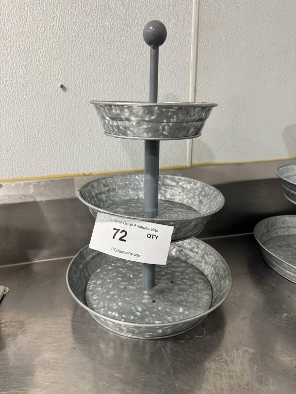 Three-tier galvanized tabletop serving tray with central handle, in good condition. Auction tag with item number 72 visible.