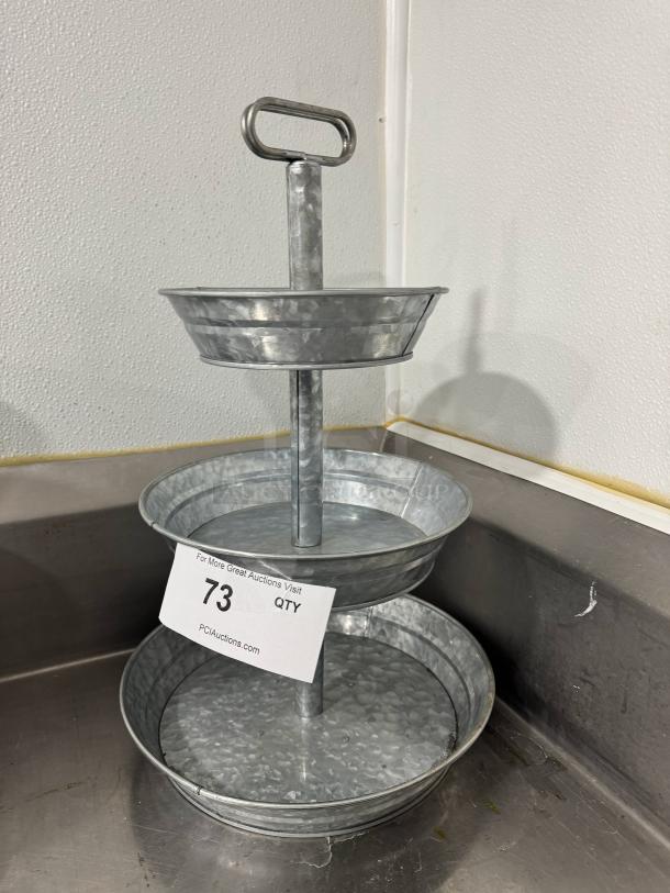 Galvanized tabletop serving tray with three tiers and a top handle, in good condition, displaying auction tag number 73.