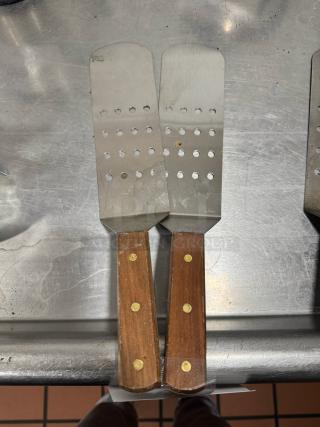 Perforated turner with wood handle, featuring dual stainless steel slotted blades. Handles have brass rivets, good condition.