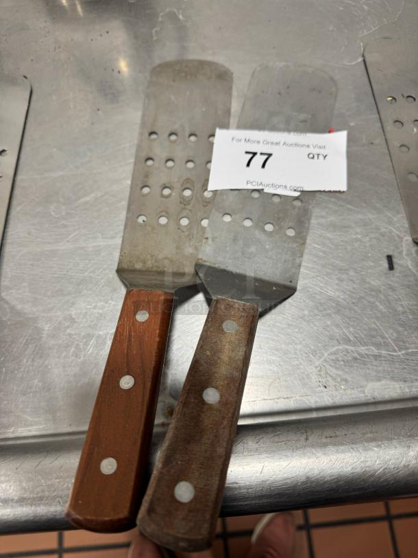 Perforated turner with wood handle, metal blade, riveted design, moderate wear. Auction tag number 77 visible.