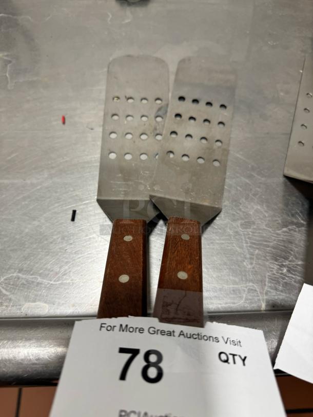 Perforated turner with wood handle, stainless steel blade, two-dot rivets, includes auction tag numbered 78.