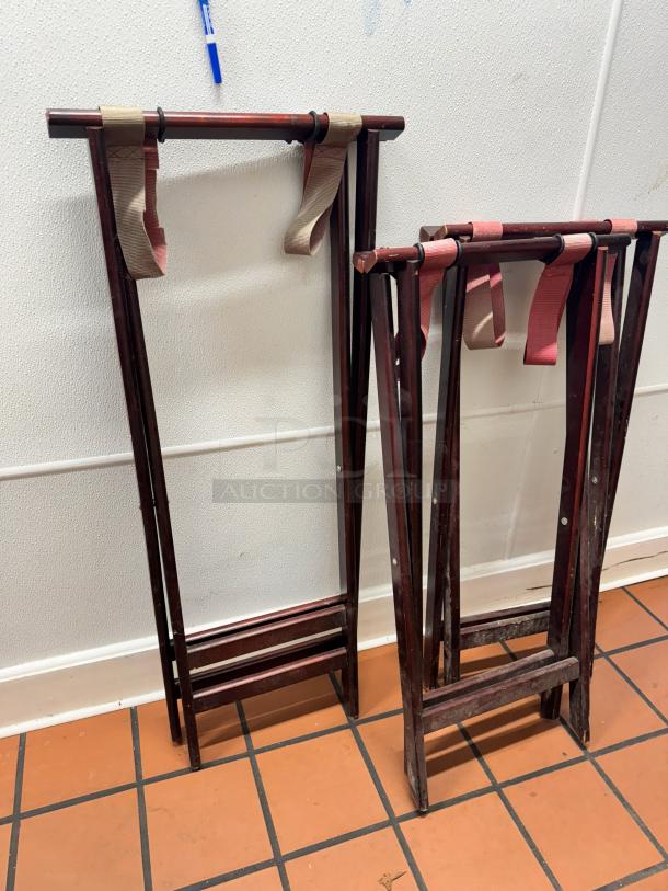 Two folding wood tray stands with straps, dark finish, in used condition. Ideal for holding trays or serving items.