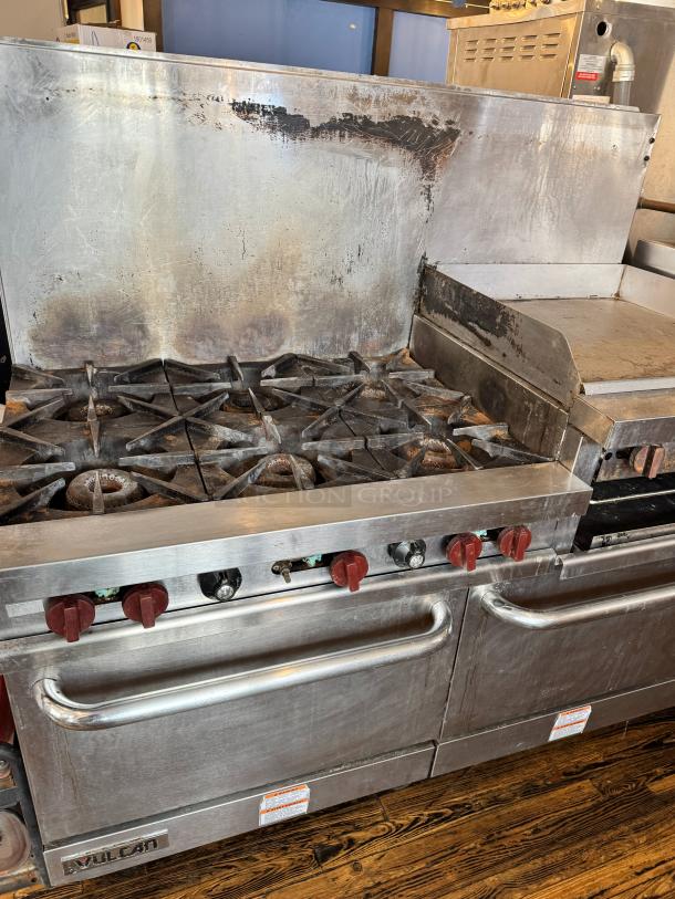 Vulcan 60" commercial gas range with griddle/broiler, two standard ovens, six burners, visible wear, and red knobs.