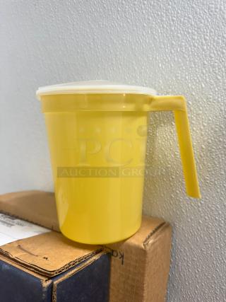 Yellow 32oz plastic pitcher, model BIDX40, with handle and lid, in excellent condition on stacked boxes.